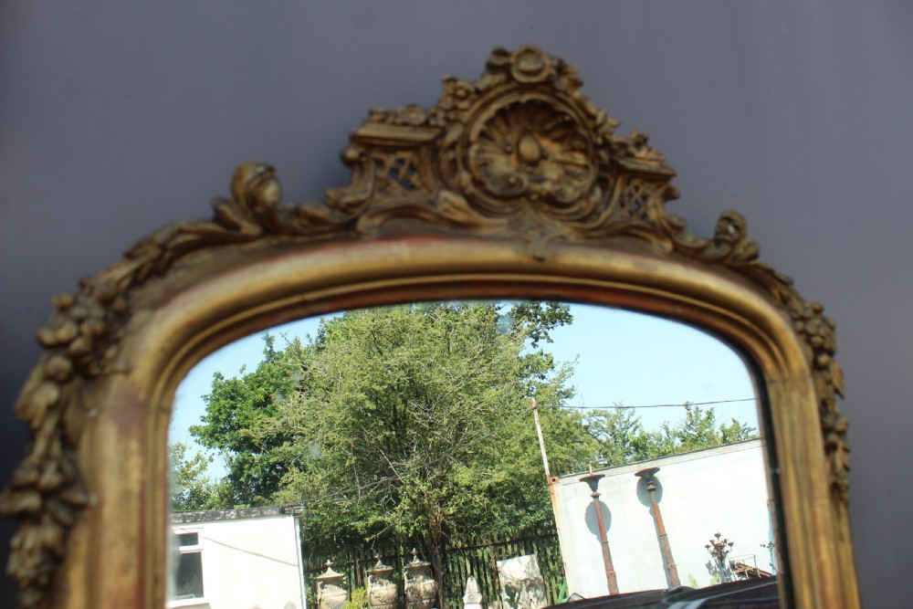 A pair of tall French giltwood pier mirrors featuring rounded arched tops with carved decorative crests and moulded frames. View IV