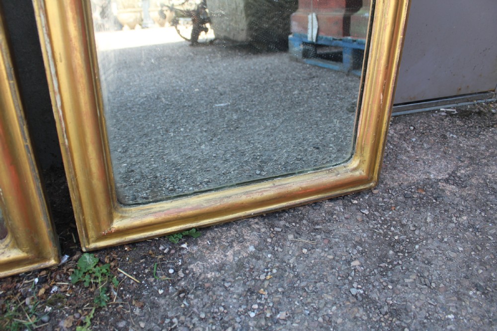 A pair of tall French giltwood pier mirrors featuring rounded arched tops with carved decorative crests and moulded frames. View V