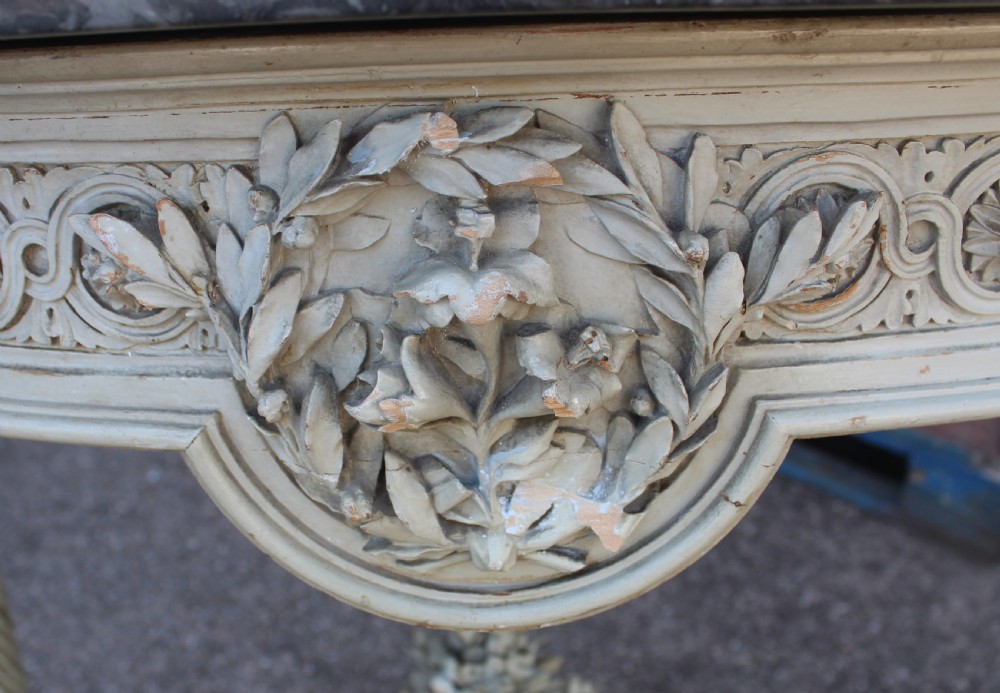 A Neoclassical French Louis XVI style demilune console table featuring a grey marble top, painted off-white carved apron, spiralled fluted legs, and a stretcher centred with a carved urn. View IV