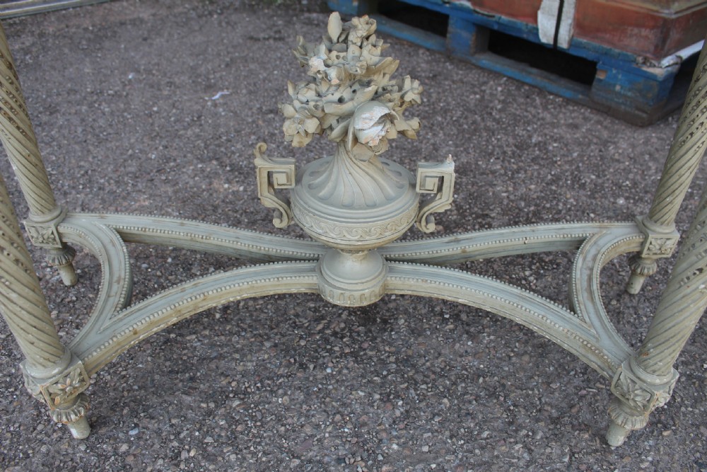 A Neoclassical French Louis XVI style demilune console table featuring a grey marble top, painted off-white carved apron, spiralled fluted legs, and a stretcher centred with a carved urn. View V