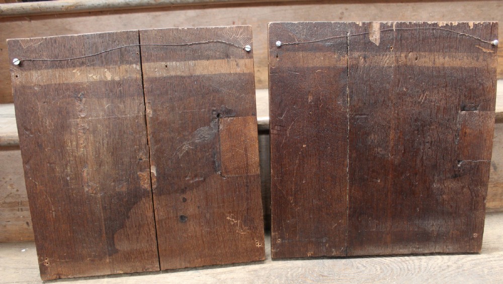 A pair of square dark oak panels featuring raised geometric mouldings surrounding central relief carvings of human faces. View IV
