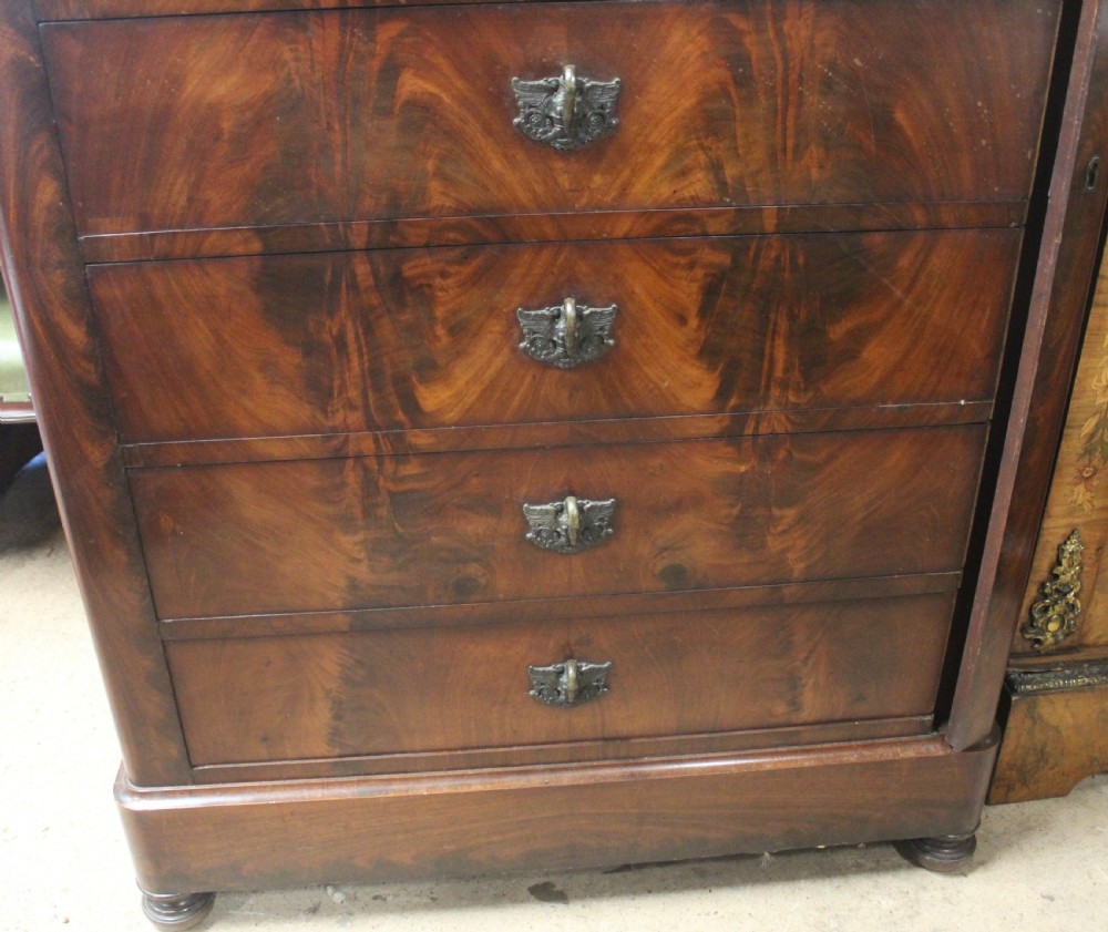 A tall 19th-century French flame mahogany semainier chest of drawers with a fitted grey marble top and ornamental brass handles. View V