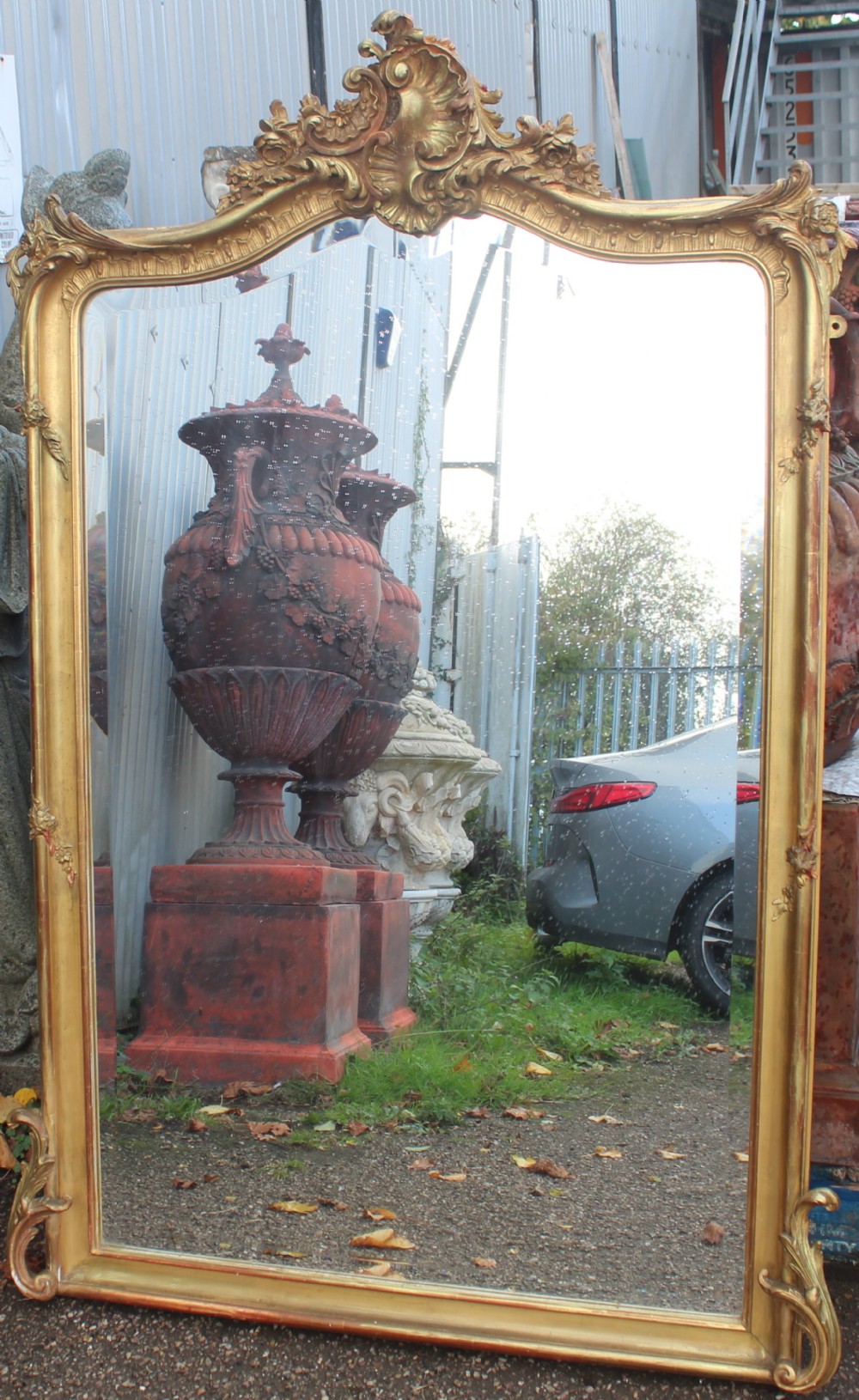 An arched antique gold giltwood overmantel mirror featuring an ornate Rococo crest with carved shell and acanthus leaf moulding.