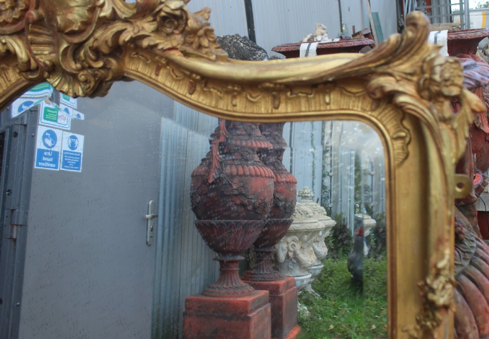 An arched antique gold giltwood overmantel mirror featuring an ornate Rococo crest with carved shell and acanthus leaf moulding. View II