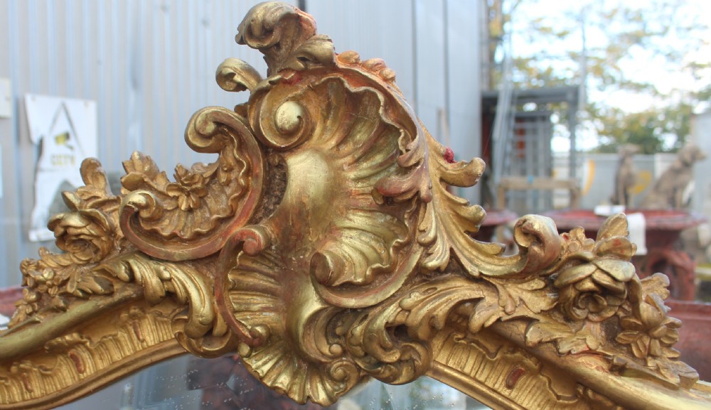 An arched antique gold giltwood overmantel mirror featuring an ornate Rococo crest with carved shell and acanthus leaf moulding. View III