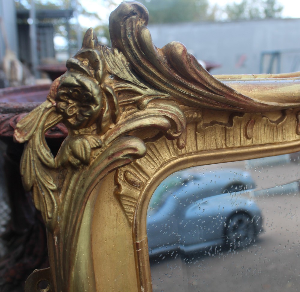 An arched antique gold giltwood overmantel mirror featuring an ornate Rococo crest with carved shell and acanthus leaf moulding. View IV