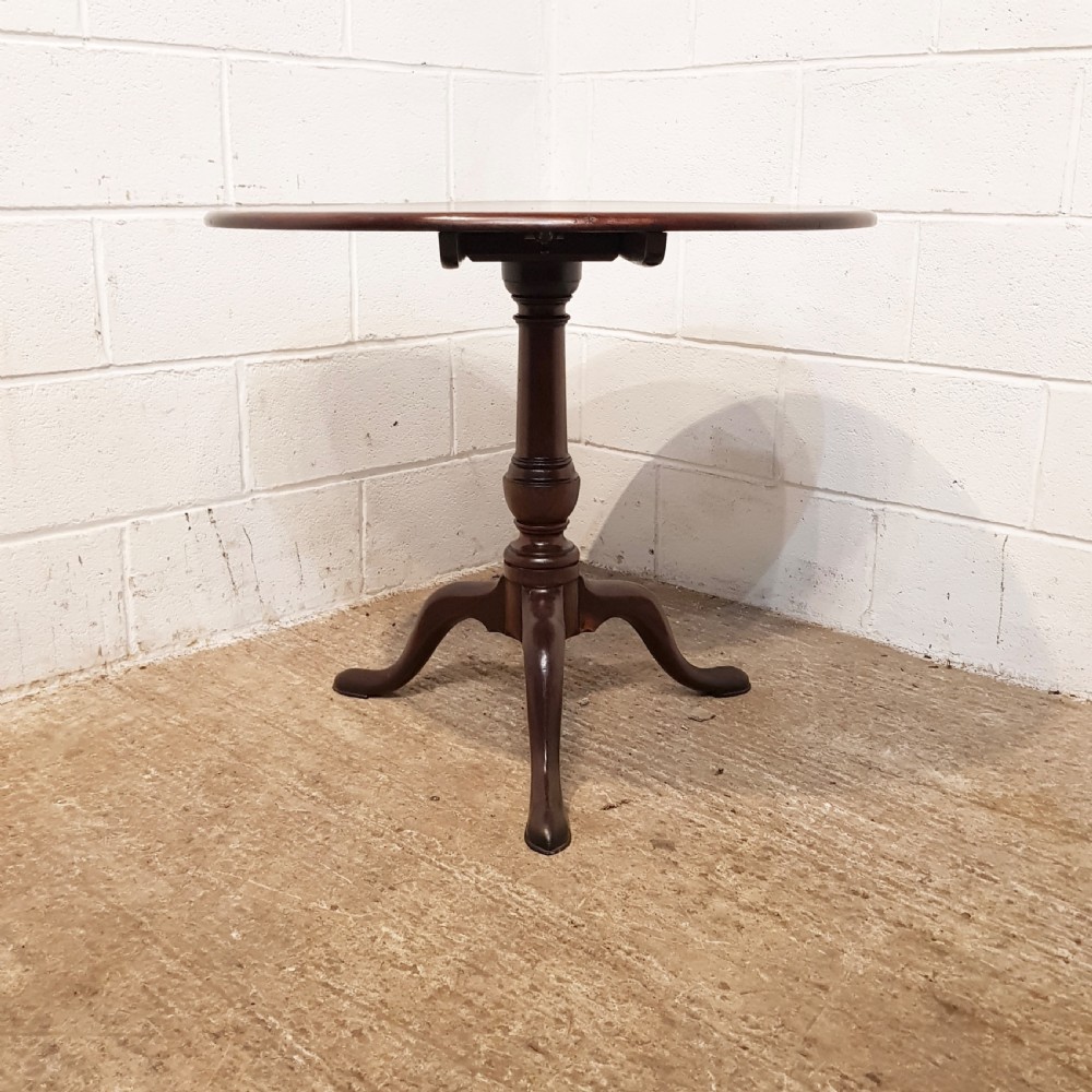 An 18th-century mahogany tilt-top table featuring a circular top displayed vertically above a turned central stem and a tripod base with pad feet. View V