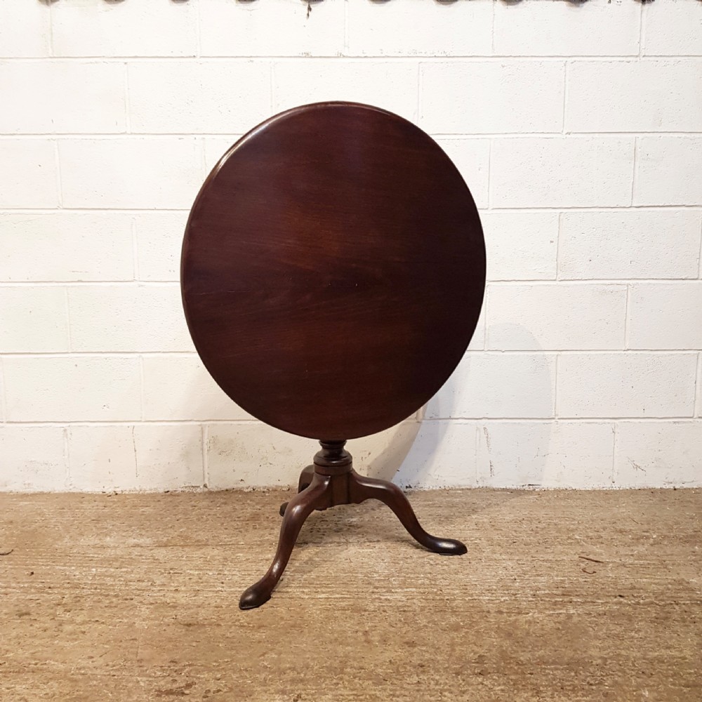 An 18th-century mahogany tilt-top table featuring a circular top displayed vertically above a turned central stem and a tripod base with pad feet. View VI
