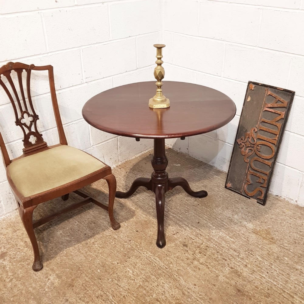 An 18th-century mahogany tilt-top table featuring a circular top displayed vertically above a turned central stem and a tripod base with pad feet. View VII