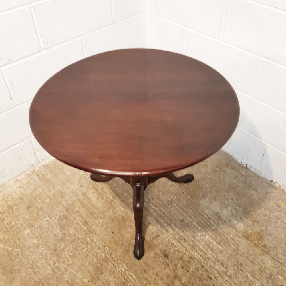 An 18th-century mahogany tilt-top table featuring a circular top displayed vertically above a turned central stem and a tripod base with pad feet. View VIII