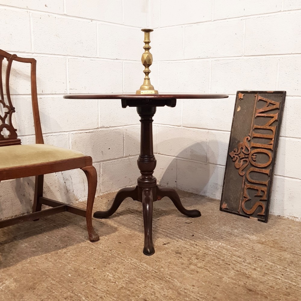 An 18th-century mahogany tilt-top table featuring a circular top displayed vertically above a turned central stem and a tripod base with pad feet. View IX