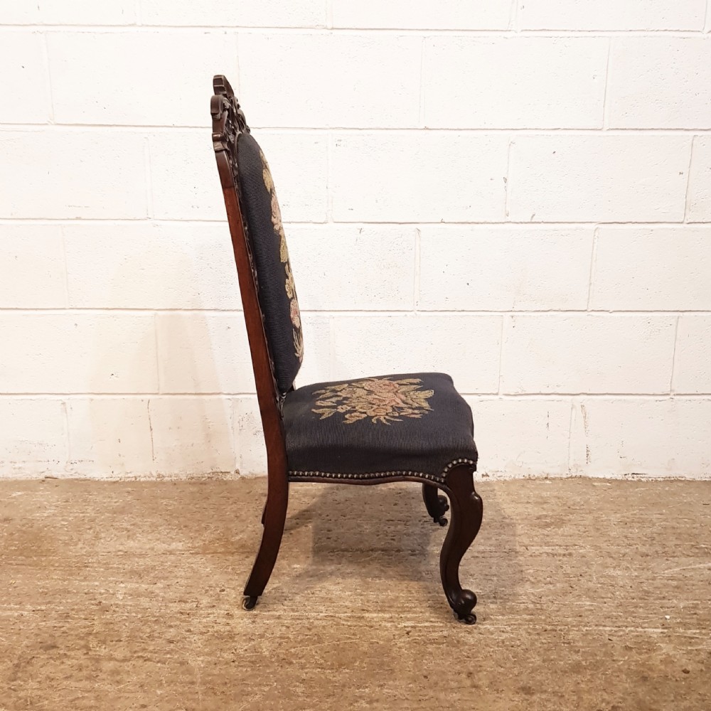 An antique Victorian carved oak hall chair featuring dark blue tapestry upholstery with floral embroidery and an openwork carved scrollwork frame. View II