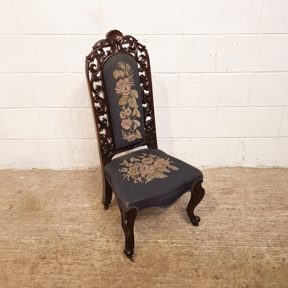 An antique Victorian carved oak hall chair featuring dark blue tapestry upholstery with floral embroidery and an openwork carved scrollwork frame. View III