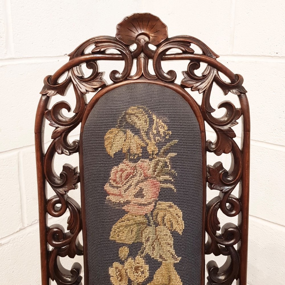 An antique Victorian carved oak hall chair featuring dark blue tapestry upholstery with floral embroidery and an openwork carved scrollwork frame. View VI