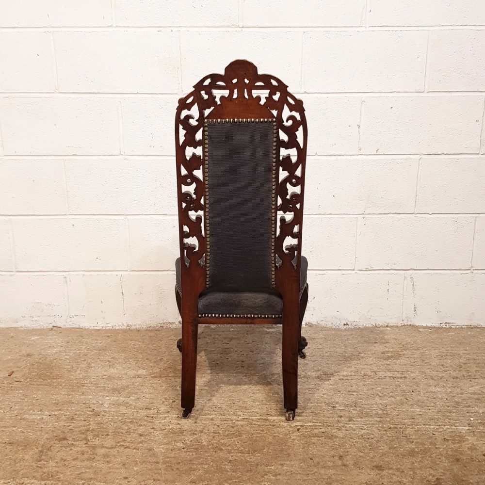 An antique Victorian carved oak hall chair featuring dark blue tapestry upholstery with floral embroidery and an openwork carved scrollwork frame. View VIII