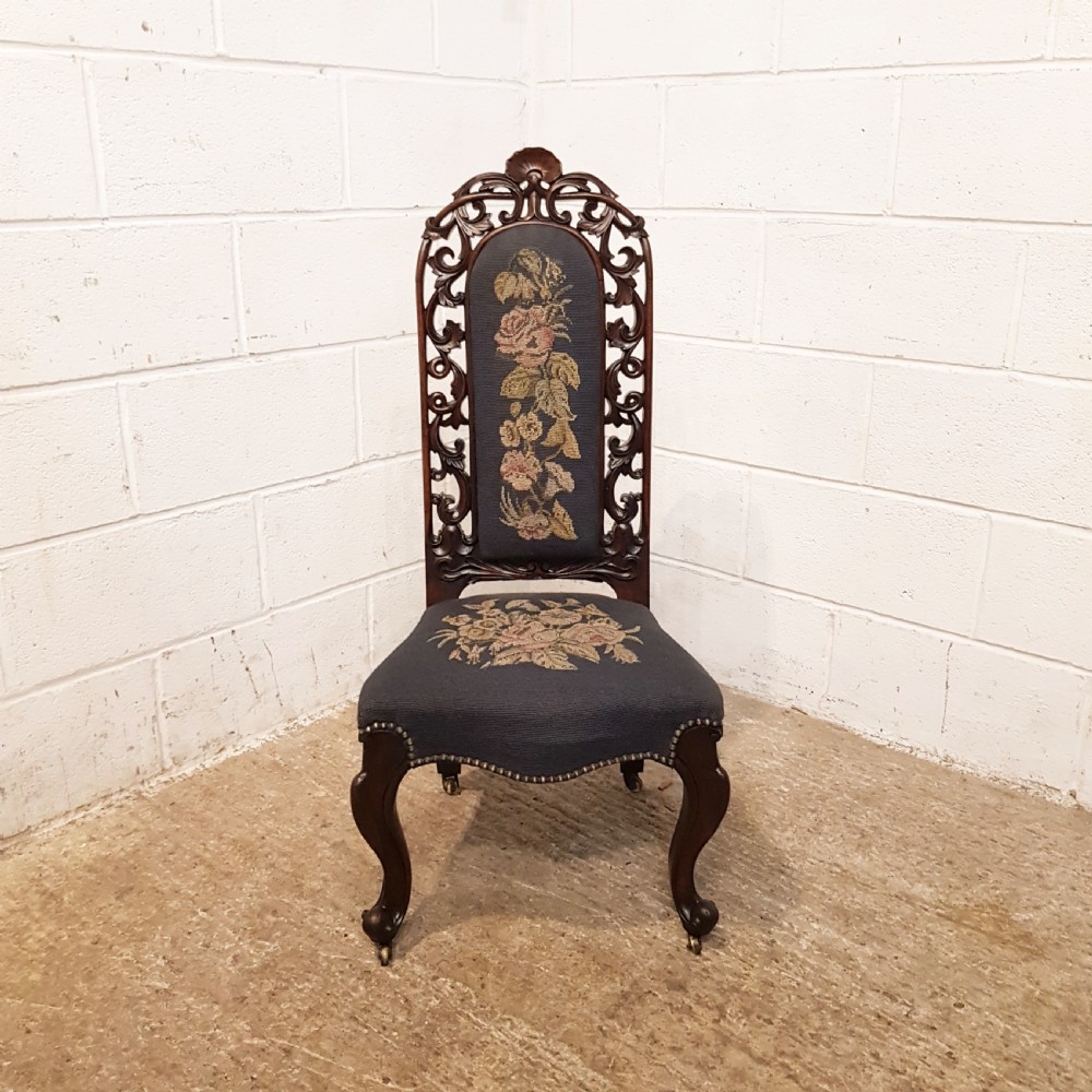 An antique Victorian carved oak hall chair featuring dark blue tapestry upholstery with floral embroidery and an openwork carved scrollwork frame. View IX