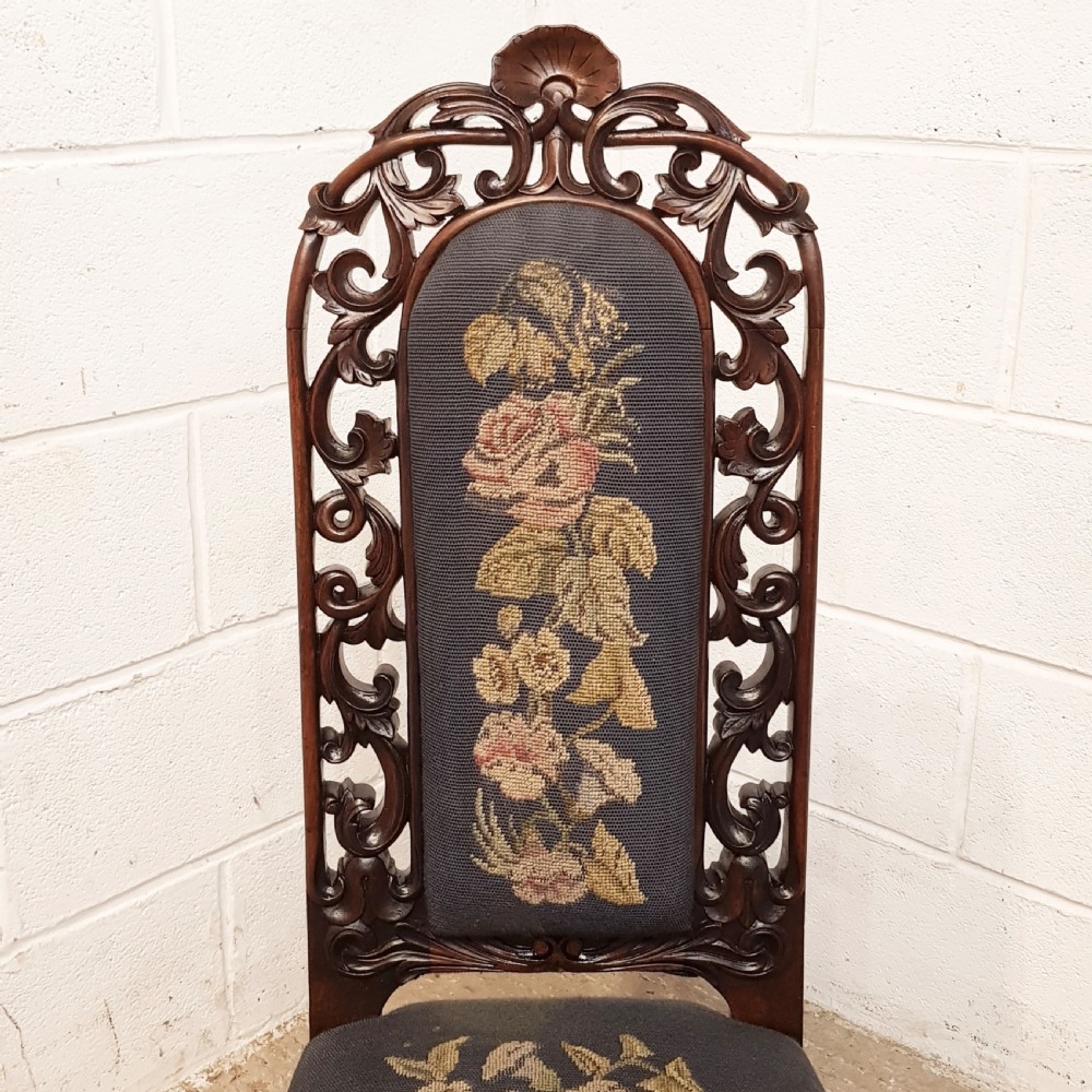 An antique Victorian carved oak hall chair featuring dark blue tapestry upholstery with floral embroidery and an openwork carved scrollwork frame. View X