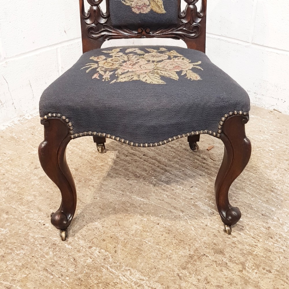 An antique Victorian carved oak hall chair featuring dark blue tapestry upholstery with floral embroidery and an openwork carved scrollwork frame. View XI