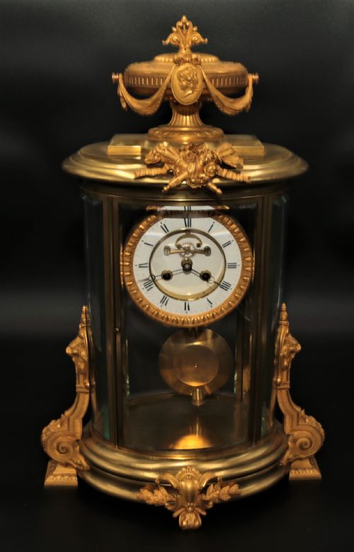 fig 1. A French Louis XVI style gilt bronze four-glass mantel clock crowned with a decorated classical urn finial and a white enamelled dial.