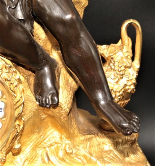 fig 1. An antique French mantel clock featuring dark bronze figures of two winged cherubs atop a gilded bronze mount and red marble base.