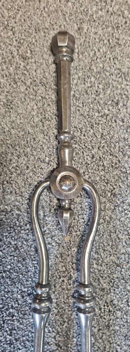 A three-piece set of Georgian polished steel fire tools comprising a poker, a pierced shovel, and a pair of tongs with faceted finials. View VIII