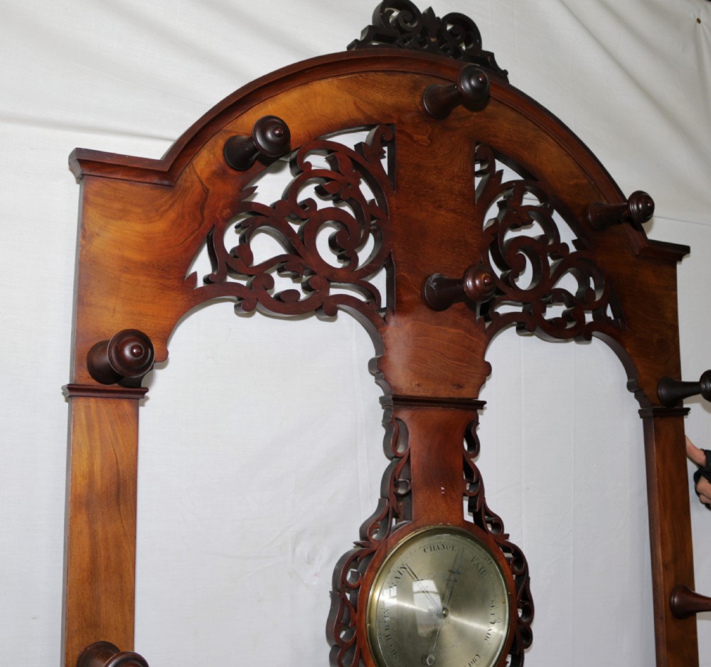 A Victorian mahogany hall stand featuring turned pegs, fretwork carving, an integrated barometer and thermometer, a white marble console surface, and lower drip trays. View II