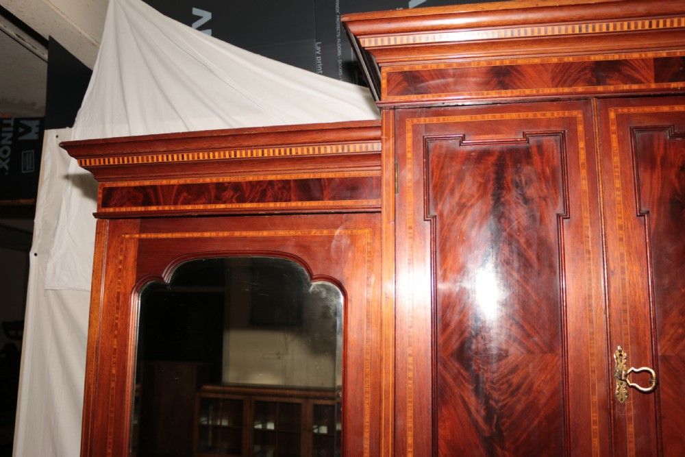A large Edwardian inlaid mahogany combination wardrobe featuring twin mirror doors flanking a central section of drawers and a upper cupboard. View V