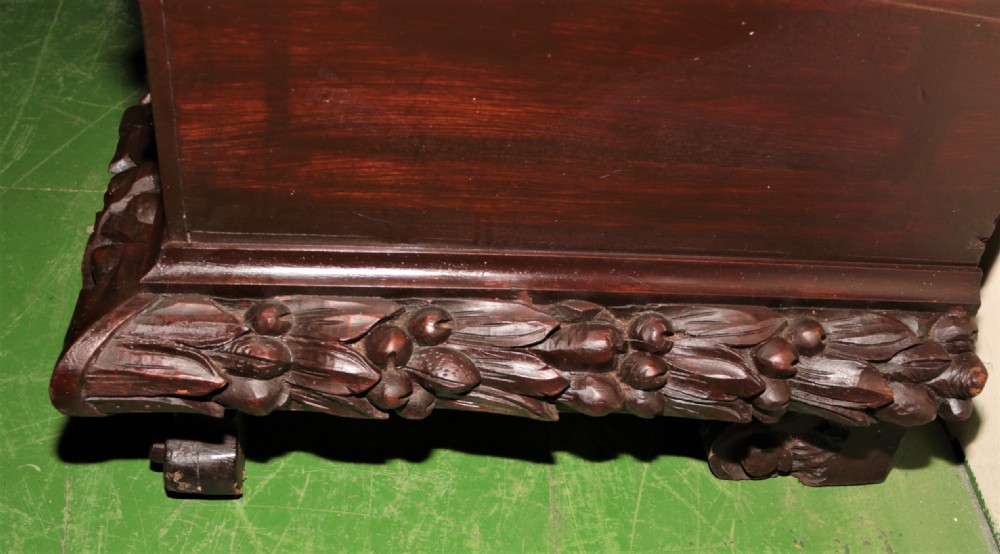A dark carved walnut hall seat featuring high-relief carvings of mythical figures and floral scrollwork on the backrest and front storage panel. View IV
