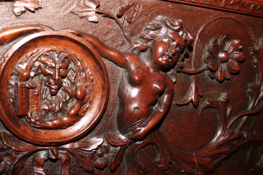 A dark carved walnut hall seat featuring high-relief carvings of mythical figures and floral scrollwork on the backrest and front storage panel. View XX