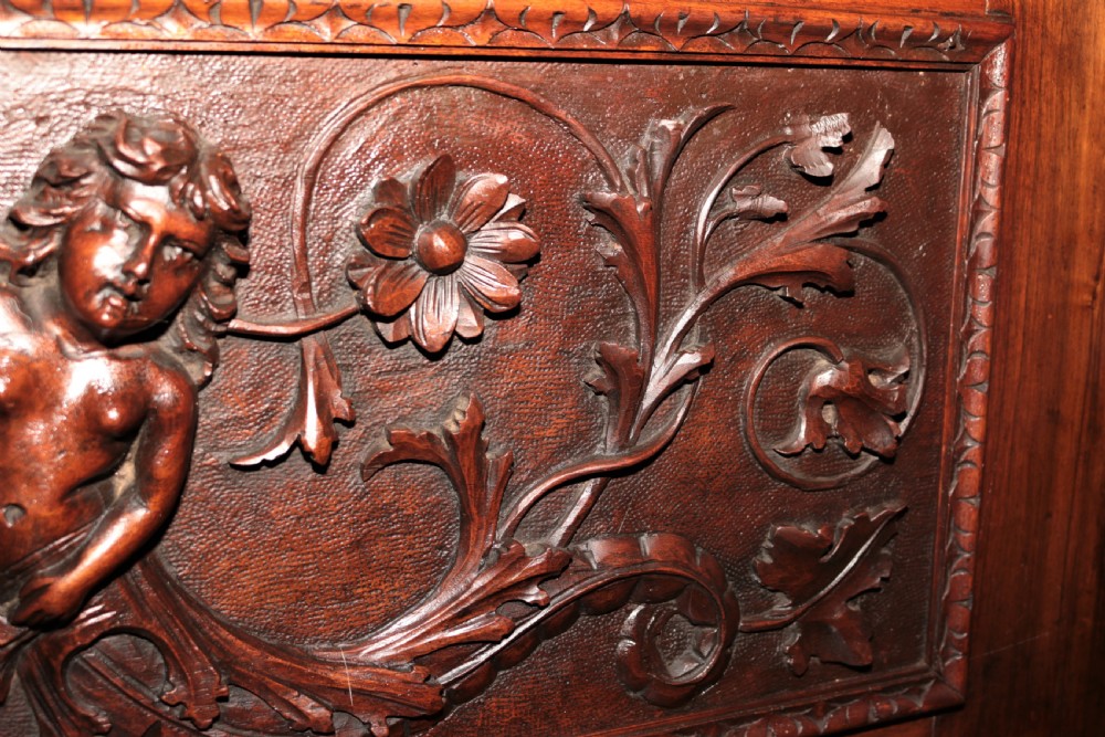 A dark carved walnut hall seat featuring high-relief carvings of mythical figures and floral scrollwork on the backrest and front storage panel. View XXII