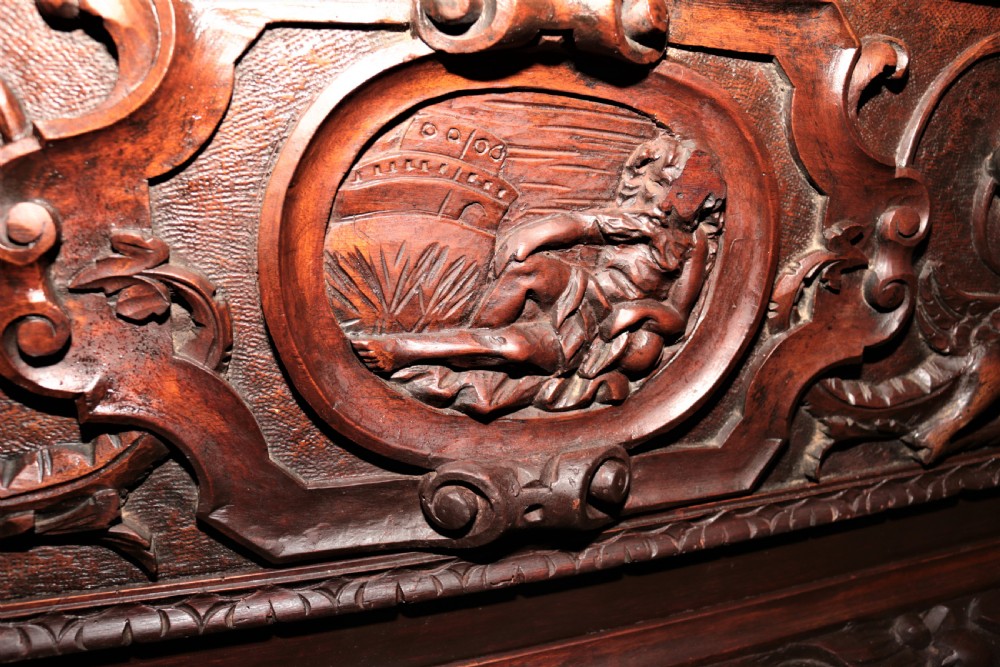 A dark carved walnut hall seat featuring high-relief carvings of mythical figures and floral scrollwork on the backrest and front storage panel. View XXV