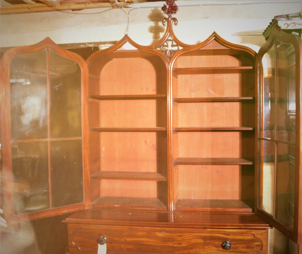 A William IV flame mahogany secretaire bookcase featuring twin arch glazed upper doors topped with a carved central finial, above a long drawer and lower cabinet section. View XI