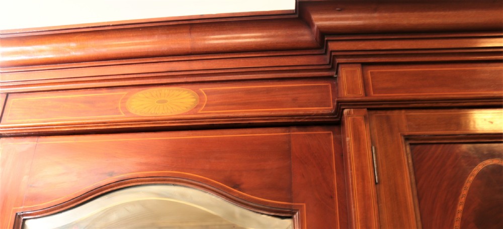 An Edwardian mahogany combination wardrobe with two outer mirrored doors, a central cupboard featuring oval satinwood inlay, an open niche, and lower drawers. View IV