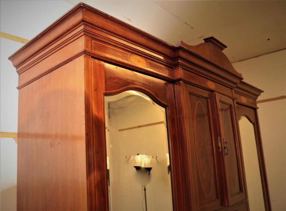An Edwardian mahogany combination wardrobe with two outer mirrored doors, a central cupboard featuring oval satinwood inlay, an open niche, and lower drawers. View VI