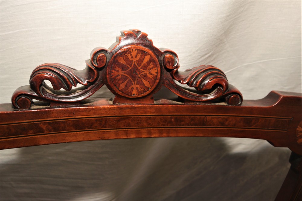 A set of four Victorian walnut side chairs featuring carved crest rails, floral marquetry inlays on the backrest, patterned brown upholstered seats, and turned front legs. View V