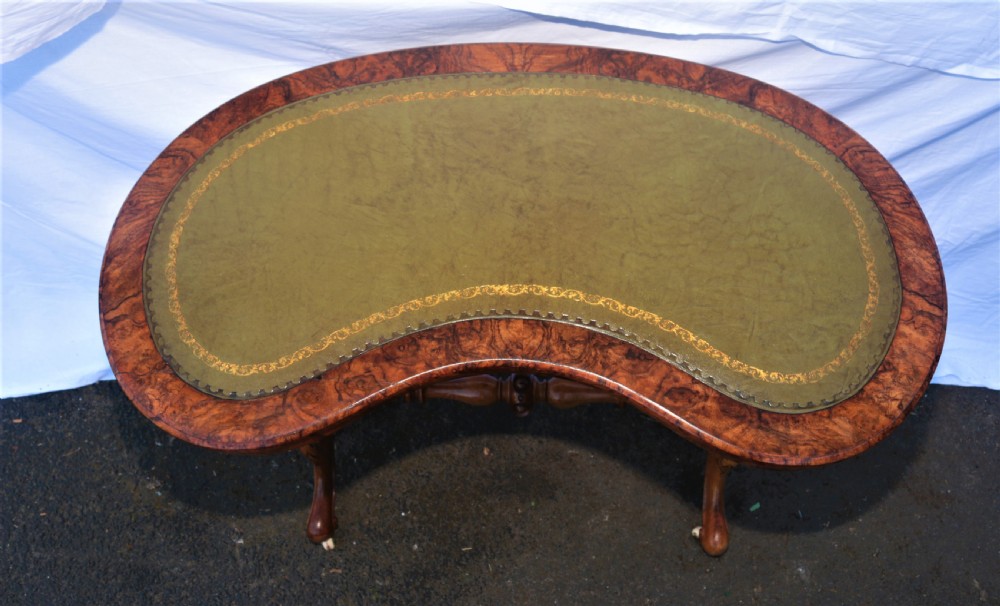 An antique kidney-shaped writing desk crafted from burr walnut with an inset green leather top, carved legs, and a central turned stretcher. View III