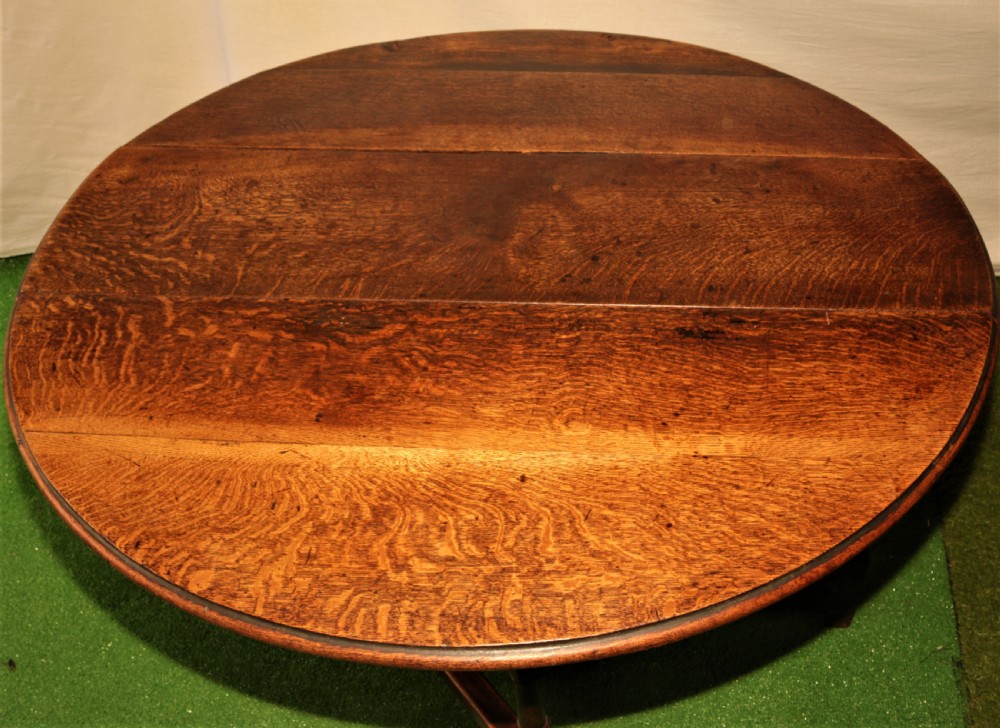 An antique oak gateleg dining table with turned baluster legs and drop-down semi-circular leaves shown in a folded position. View V