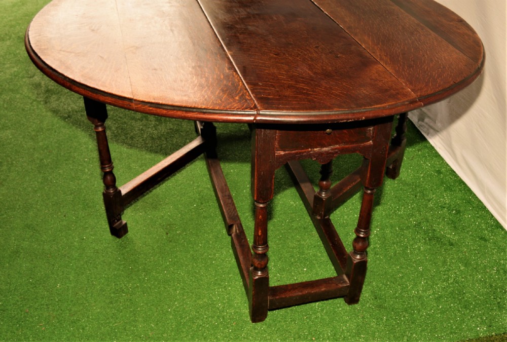 An antique oak gateleg dining table with turned baluster legs and drop-down semi-circular leaves shown in a folded position. View VIII