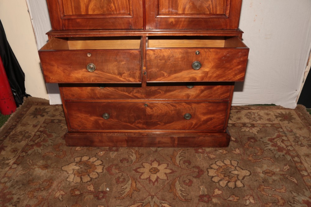 A Victorian flame mahogany linen press with a moulded cornice, arched double doors on the upper cabinet, and four drawers in the lower section. View V