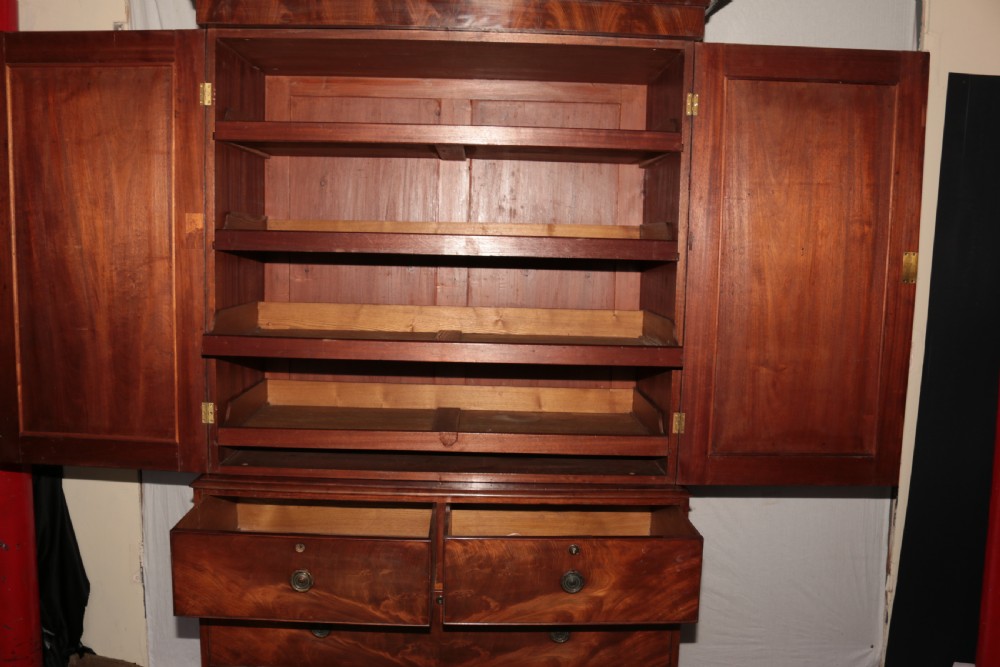 A Victorian flame mahogany linen press with a moulded cornice, arched double doors on the upper cabinet, and four drawers in the lower section. View VII