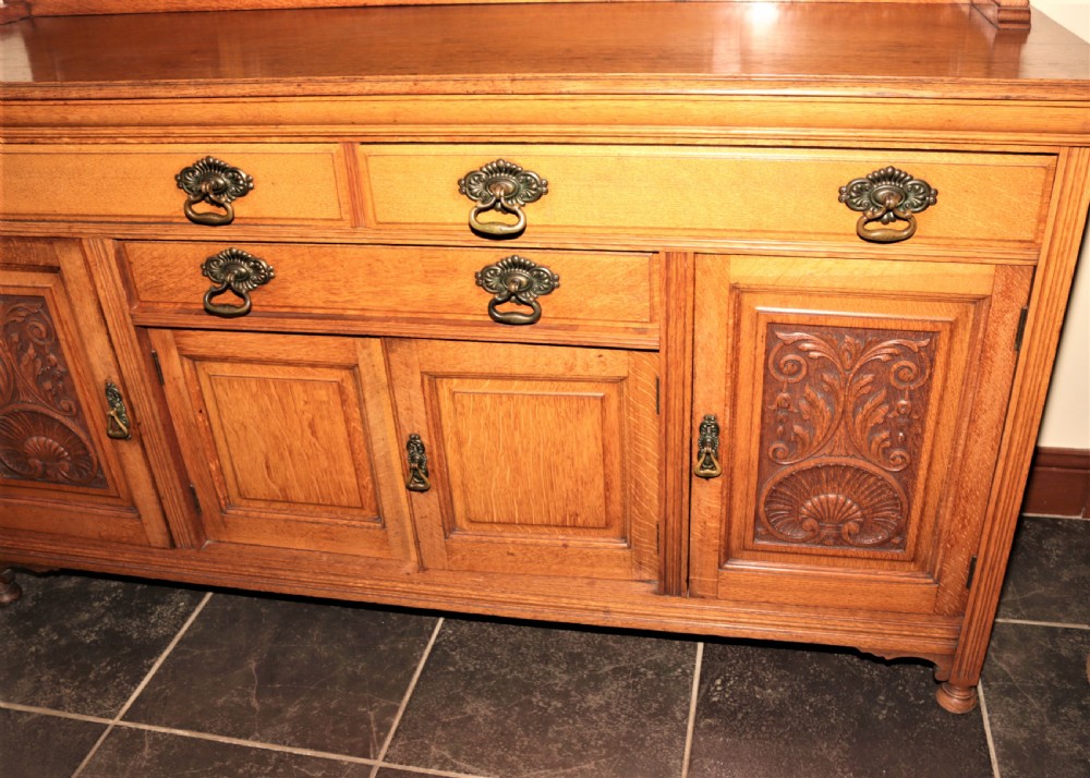 A late Victorian carved oak sideboard featuring a mirrored superstructure, drawers, and carved cupboard doors. View III