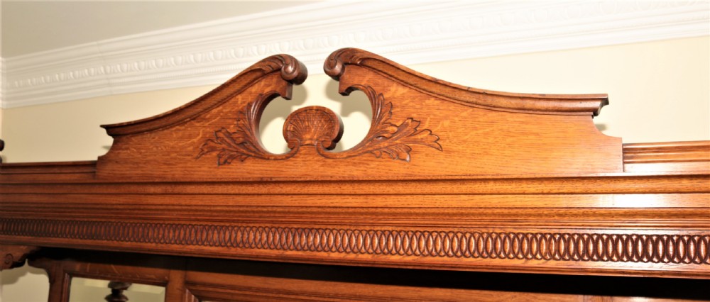A late Victorian carved oak sideboard featuring a mirrored superstructure, drawers, and carved cupboard doors. View VII