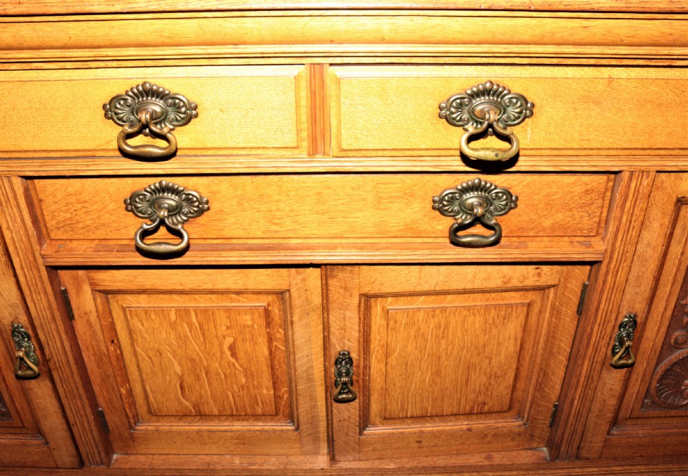 A late Victorian carved oak sideboard featuring a mirrored superstructure, drawers, and carved cupboard doors. View VIII