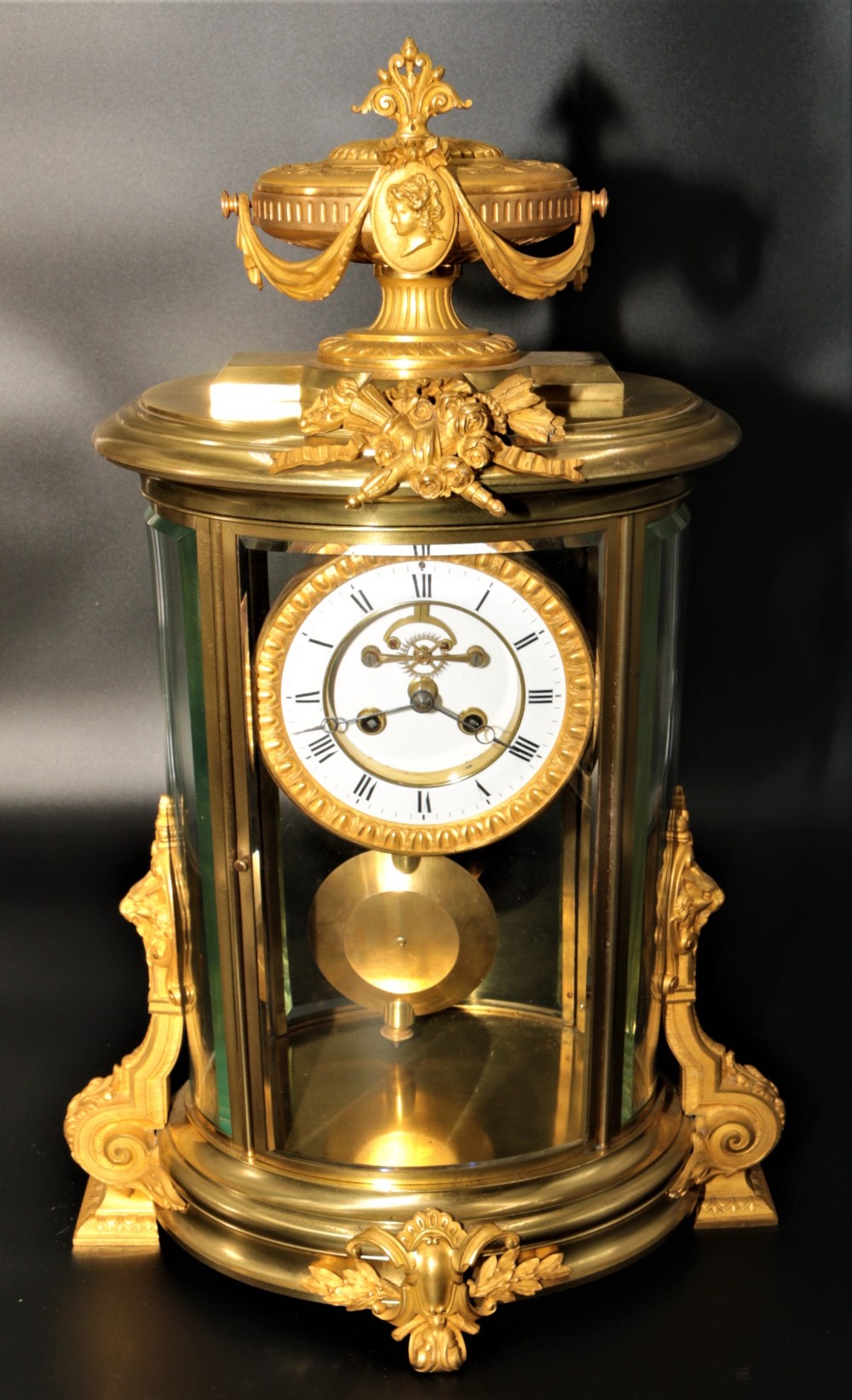 A French Louis XVI style gilt bronze four-glass mantel clock crowned with a decorated classical urn finial and a white enamelled dial.