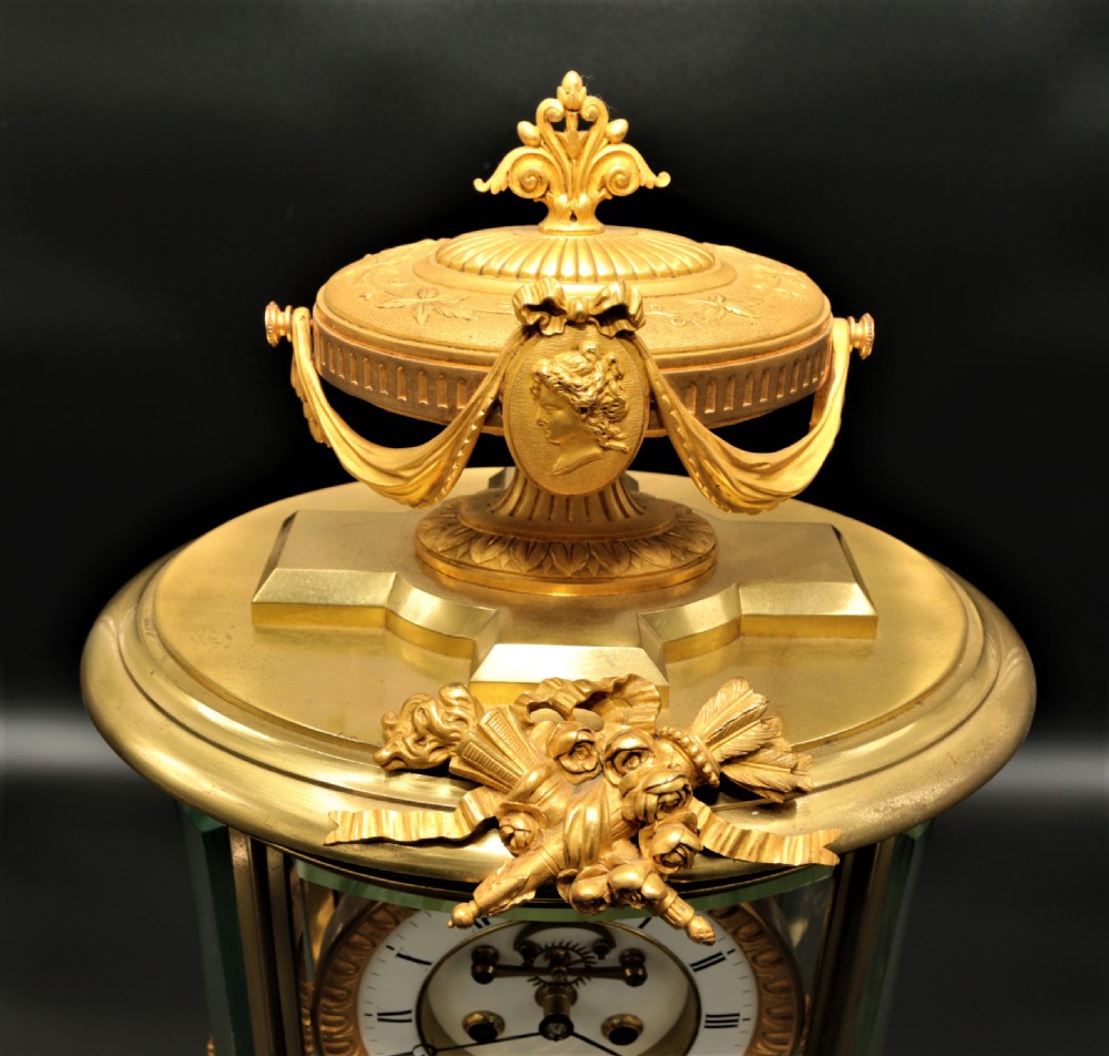 A French Louis XVI style gilt bronze four-glass mantel clock crowned with a decorated classical urn finial and a white enamelled dial. View V