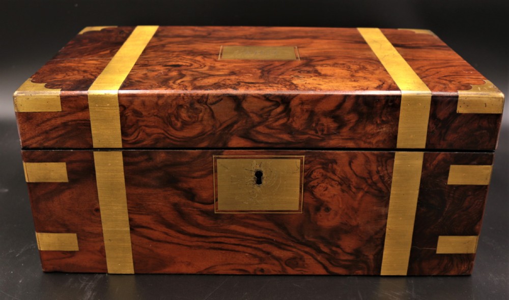 A rectangular Victorian burr walnut writing box featuring brass straps, corner mounts, an engraved central cartouche, and an escutcheon keyhole. View VII