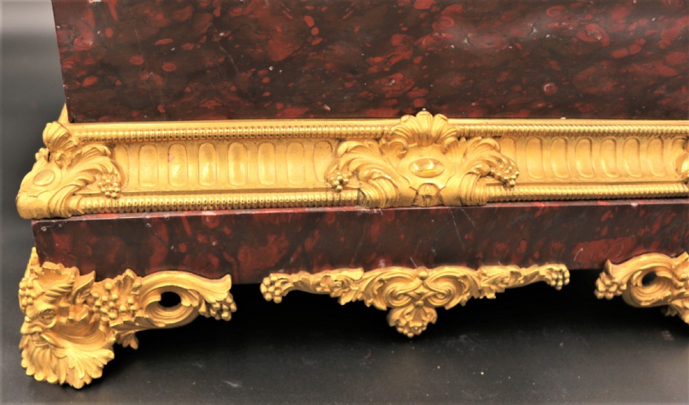 An antique French mantel clock featuring dark bronze figures of two winged cherubs atop a gilded bronze mount and red marble base. View IV