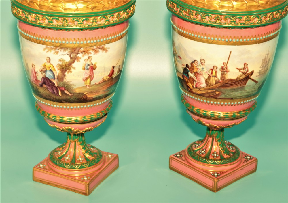 A pair of hand-painted pink porcelain urns featuring romantic pastoral figures, green detailing, intricate gilding, and square pedestal bases. View III