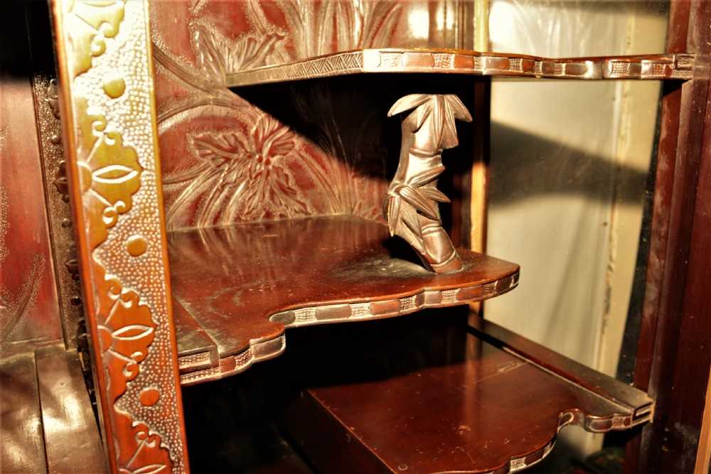 Intricately carved dark hardwood oriental display cabinet featuring high-relief dragon motifs, asymmetric glass-enclosed shelves, and floral back panels. View III