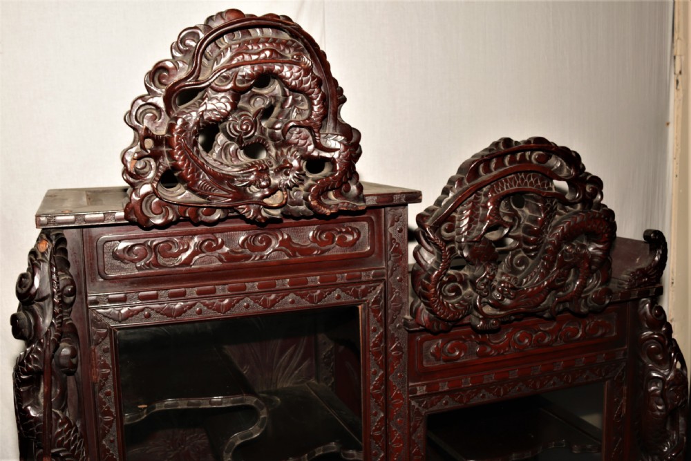 Intricately carved dark hardwood oriental display cabinet featuring high-relief dragon motifs, asymmetric glass-enclosed shelves, and floral back panels. View IV